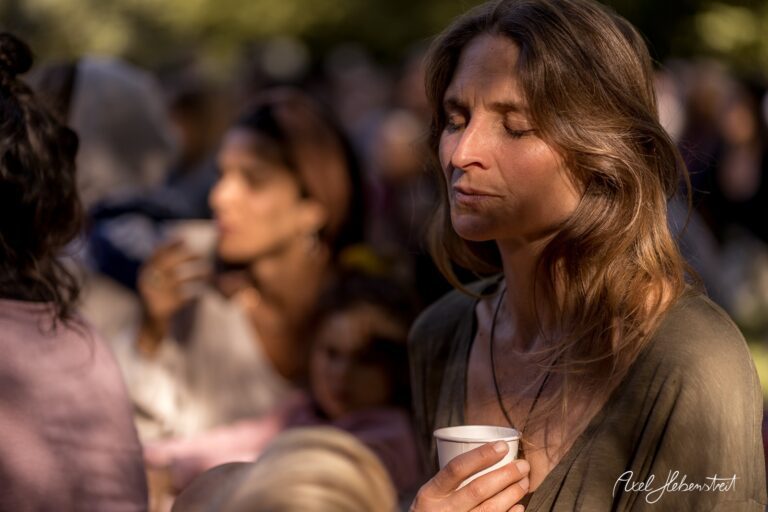 Frau in entspannter Meditation mit einer Tasse in der Hand, umgeben von festlicher Atmosphäre im Freien – © Axel Hebenstreit