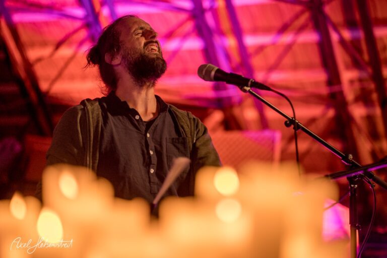 Musiker mit geschlossenen Augen und leidenschaftlichem Ausdruck singt vor einem stimmungsvollen Kerzenlicht – © Axel Hebenstreit