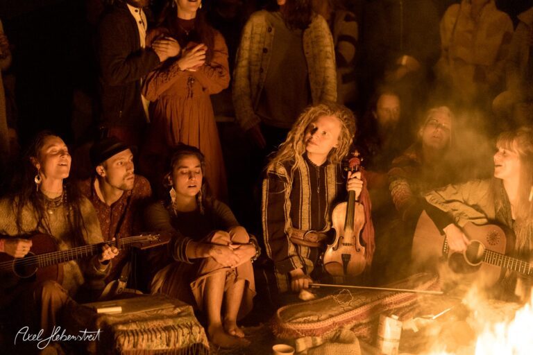 Eine Gruppe von Menschen spielt Musik am Lagerfeuer und genießt die Gemeinschaft bei einem Festival. – © Axel Hebenstreit