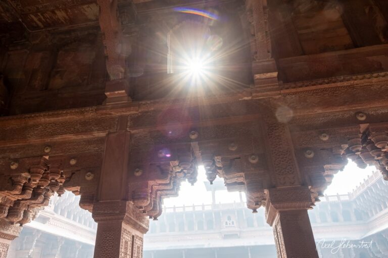 Lichtstrahlen fallen durch kunstvoll verzierte Säulen in einem historischen Gebäude – © Axel Hebenstreit