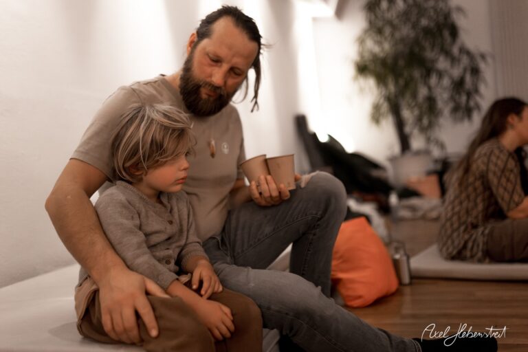 Vater und Sohn sitzen gemeinsam entspannt in einem modernen Raum, umgeben von einer ruhigen Atmosphäre. – © Axel Hebenstreit