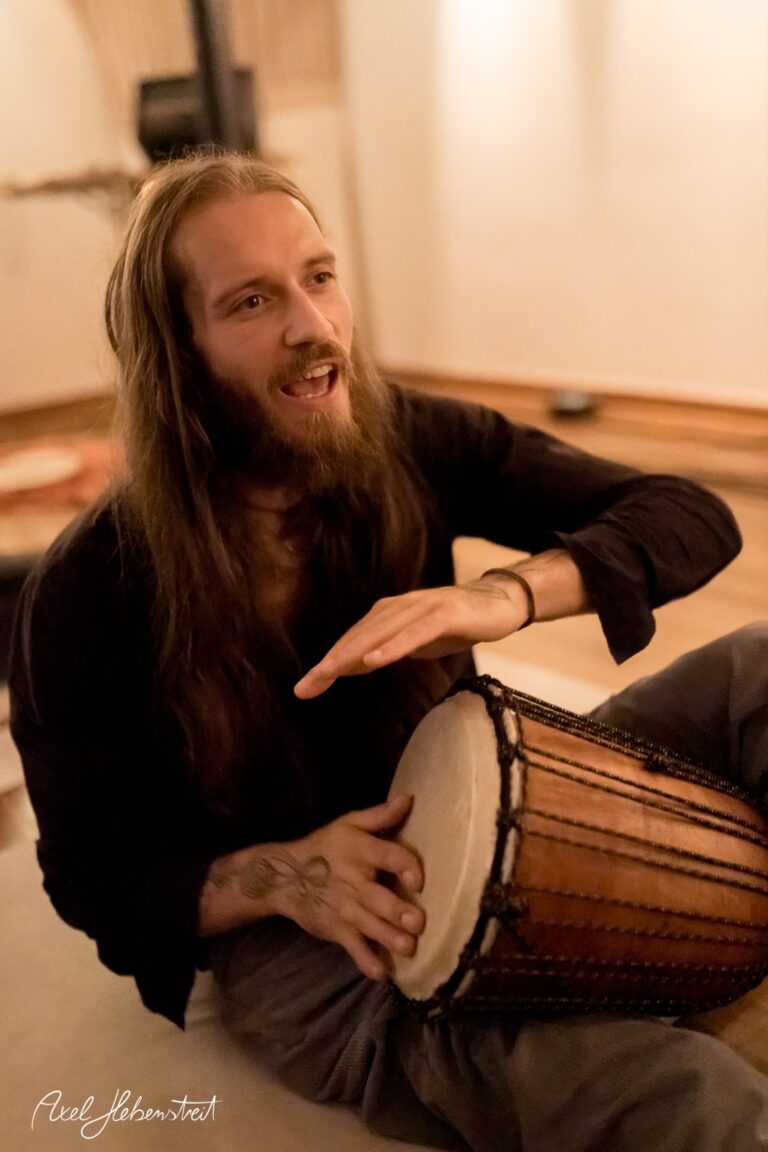 Ein Musiker spielt begeistert auf einem Trommelinstrument in einer entspannten, intime Atmosphäre. – © Axel Hebenstreit