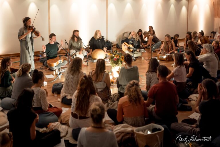 Musiker*innen spielen in einem harmonischen Kreis, umgeben von einer entspannten Zuhörerschaft – © Axel Hebenstreit