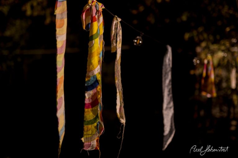 Bunte Stoffstreifen hängen an einer Schnur vor dunklem Hintergrund, schaffen eine festliche Stimmung – © Axel Hebenstreit