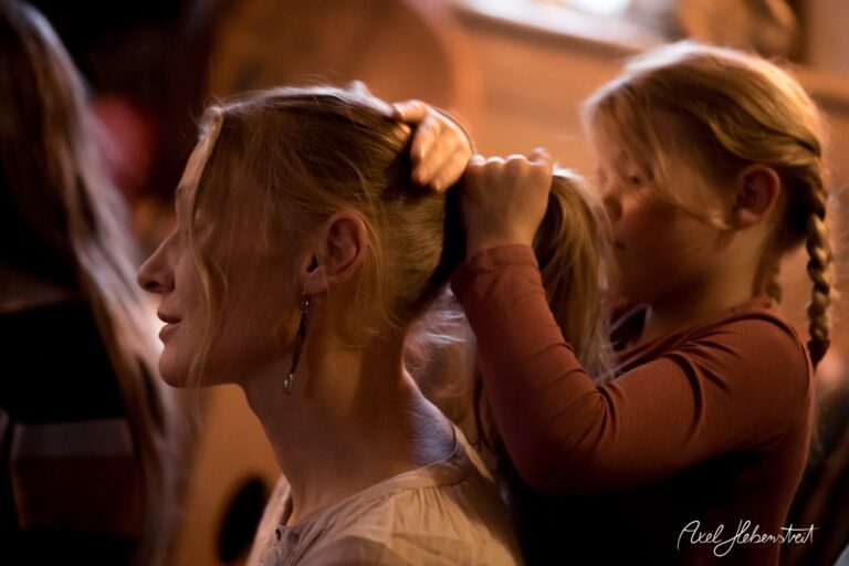 Eine Frau sitzt entspannt, während ein Mädchen ihr die Haare zu einem Pferdeschwanz bindet – © Axel Hebenstreit.