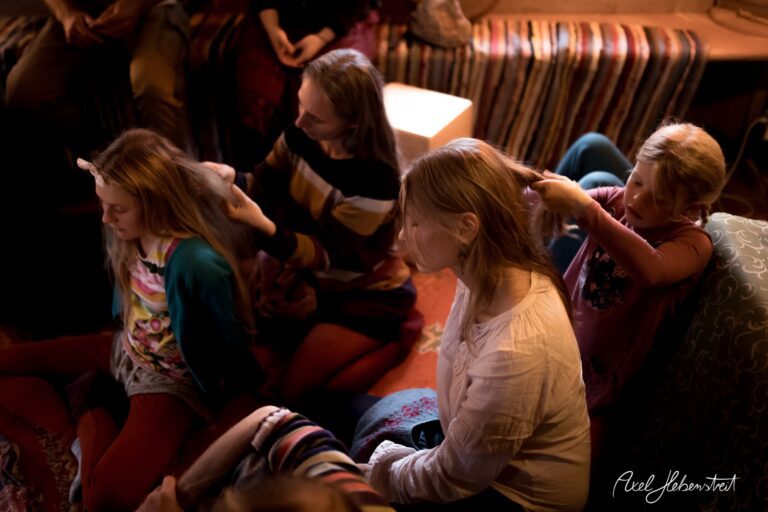 Eine Gruppe von Frauen und Mädchen sitzt entspannt zusammen, während eines die Haare einer anderen frisiert – © Axel Hebenstreit.