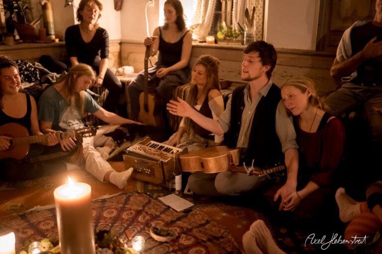 In einer warmen, gemütlichen Umgebung musizieren mehrere Menschen gemeinsam bei Kerzenlicht. – © Axel Hebenstreit