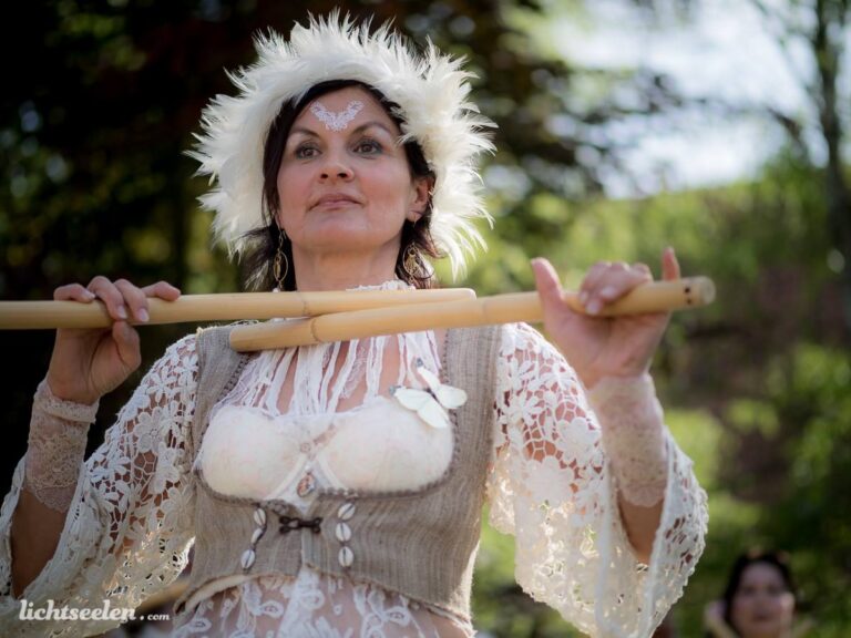 Frau in folkloristischer Kleidung spielt eine Flöte und strahlt eine kulturelle Atmosphäre aus, umgeben von Natur.