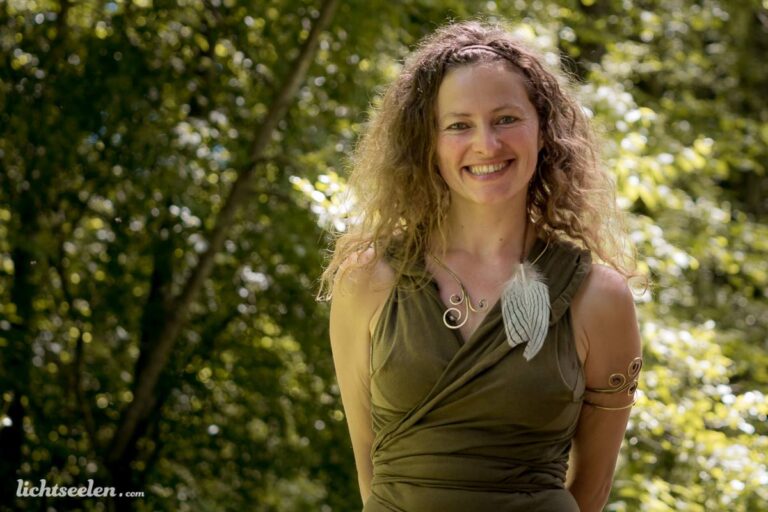 Lächelnde Frau im Wald, tragt ein elegantes Kleid und zarte Schmuckstücke, vermittelt eine fröhliche und harmonische Stimmung.