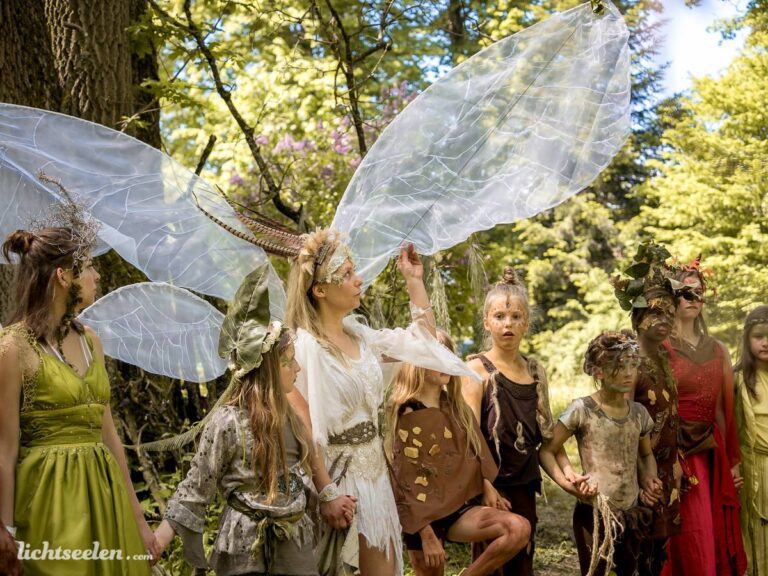 Gruppierung von fantasievoll kostümierten Wesen im Wald, die den Zauber einer Märchenwelt ausstrahlen.