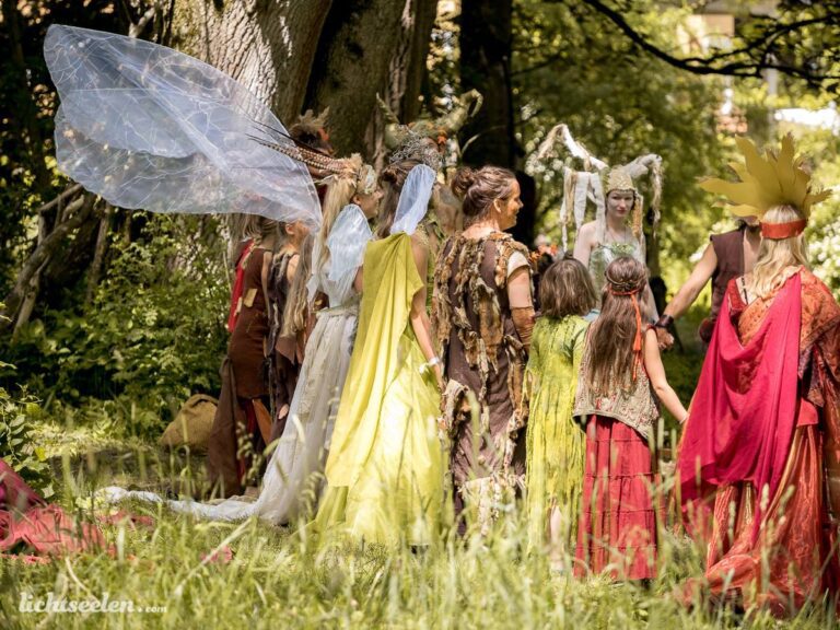 Gruppierung von Menschen in fantasievollen Kostümen in einer natürlichen Umgebung, die eine magische Atmosphäre ausstrahlt.