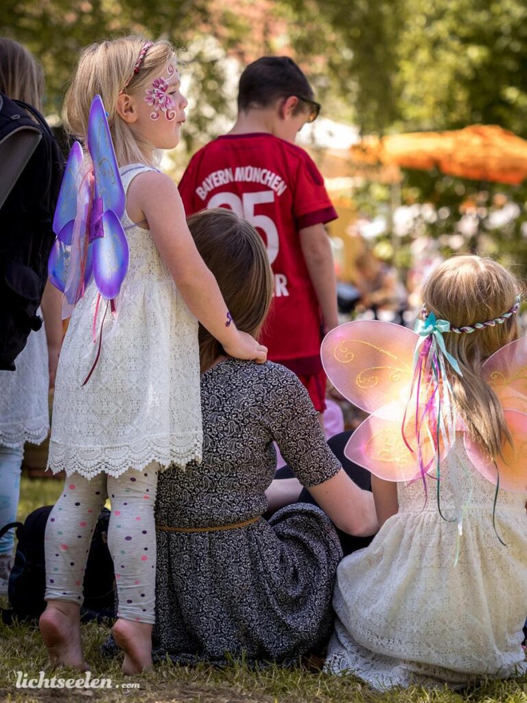 Kinder mit Flügeln genießen eine fröhliche Zeit im Freien während eines Festivals in Bayern.