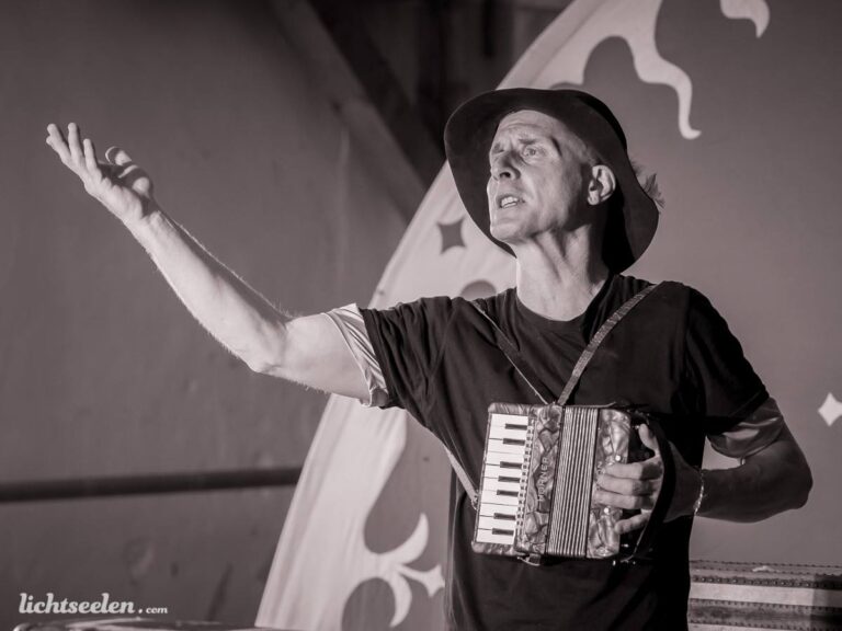 Ein Musiker mit Akkordeon, in leidenschaftlicher Pose, sorgt für Stimmung auf einer Festivalbühne.