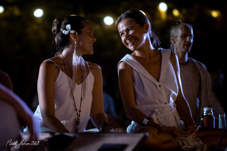 Zwei Frauen lachen entspannt miteinander bei einem Abend-Event unter Lichtern – © Axel Hebenstreit