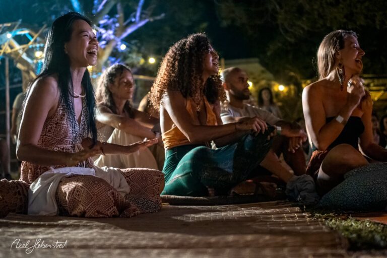 Lachende Menschen sitzen im Kreis bei einer lebendigen Yoga- oder Musikveranstaltung unter angenehmem Licht – © Axel Hebenstreit