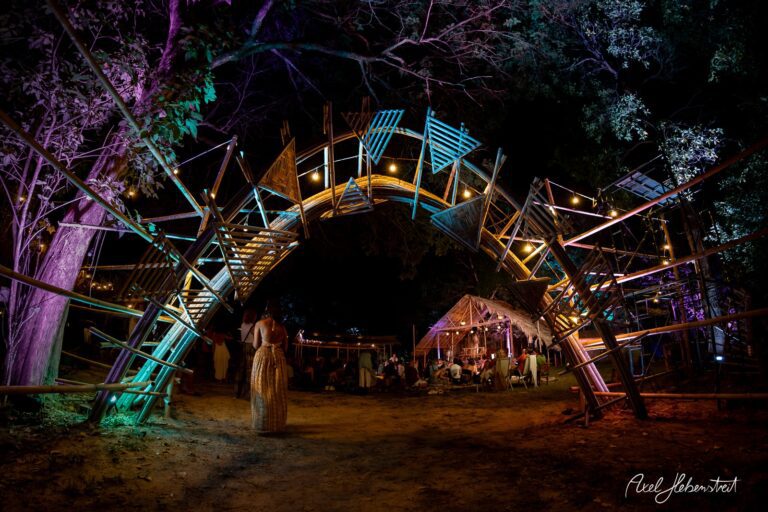 Bunte Lichtinstallationen formen einen einladenden Bogen an einem Festivalort im Freien. – © Axel Hebenstreit