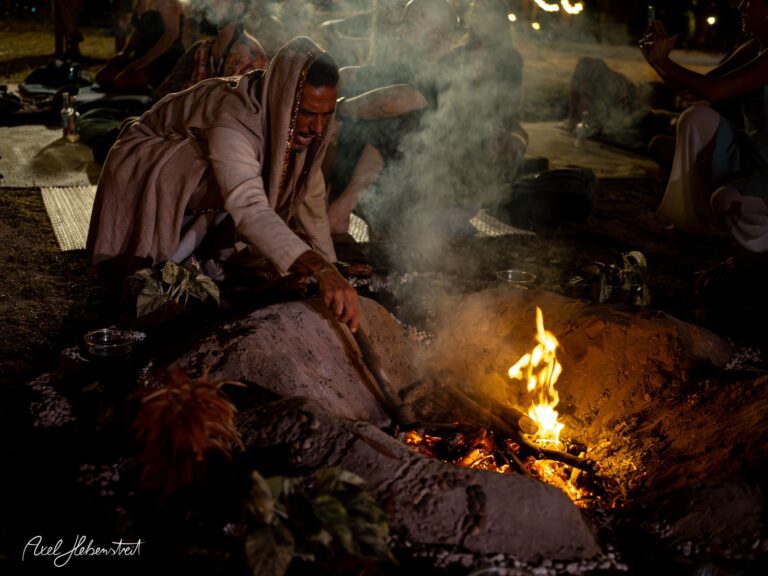 Ein Mann sitzt am Feuer, rührt mit einem Stock und schafft eine meditative, festliche Atmosphäre. – © Axel Hebenstreit