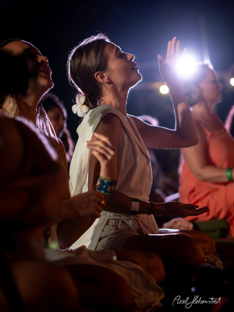 Frau in meditativer Pose bei einem Festival, umgeben von sanftem Licht und einer entspannten Atmosphäre – © Axel Hebenstreit