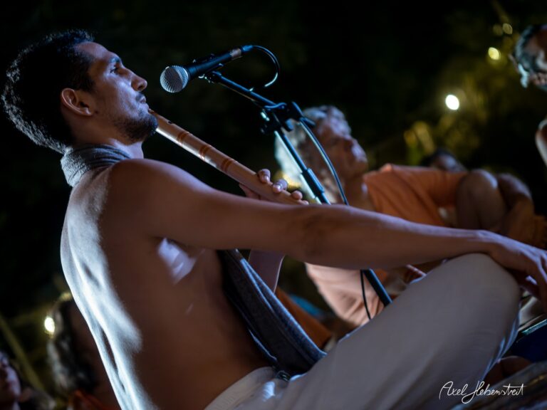Ein Musiker spielt flötenspielend in einer harmonischen Atmosphäre während einer Yoga-Veranstaltung im Freien – © Axel Hebenstreit.