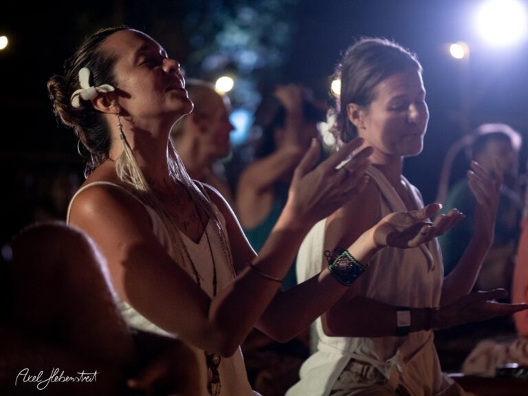 Zwei Frauen in meditativer Pose während einer Veranstaltung unter Lichtern, umgeben von einer entspannten Atmosphäre – © Axel Hebenstreit