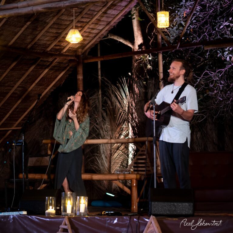 Zwei Musiker performen leidenschaftlich unter einem strohgedeckten Dach im Kerzenlicht – © Axel Hebenstreit