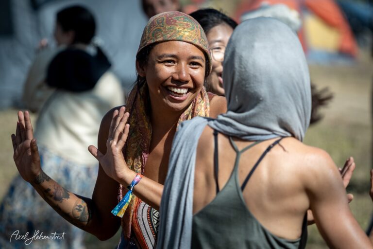 Lächelnde Frauen tanzen fröhlich miteinander auf einem Festival im Freien – © Axel Hebenstreit