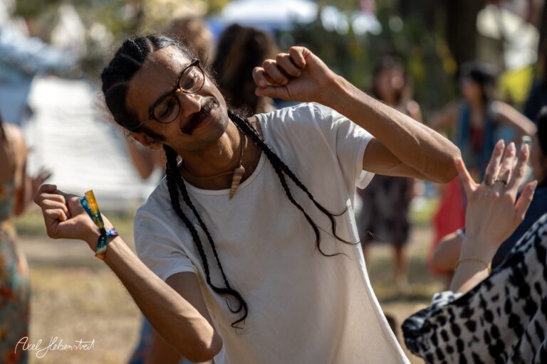 Junger Mann mit Zöpfen tanzt ausgelassen auf einem Festival im Freien – © Axel Hebenstreit