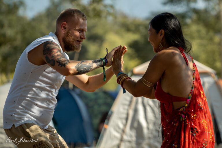 Tanzende Menschen voller Freude in festlicher Kleidung auf einem Festivalgelände in der Natur – © Axel Hebenstreit