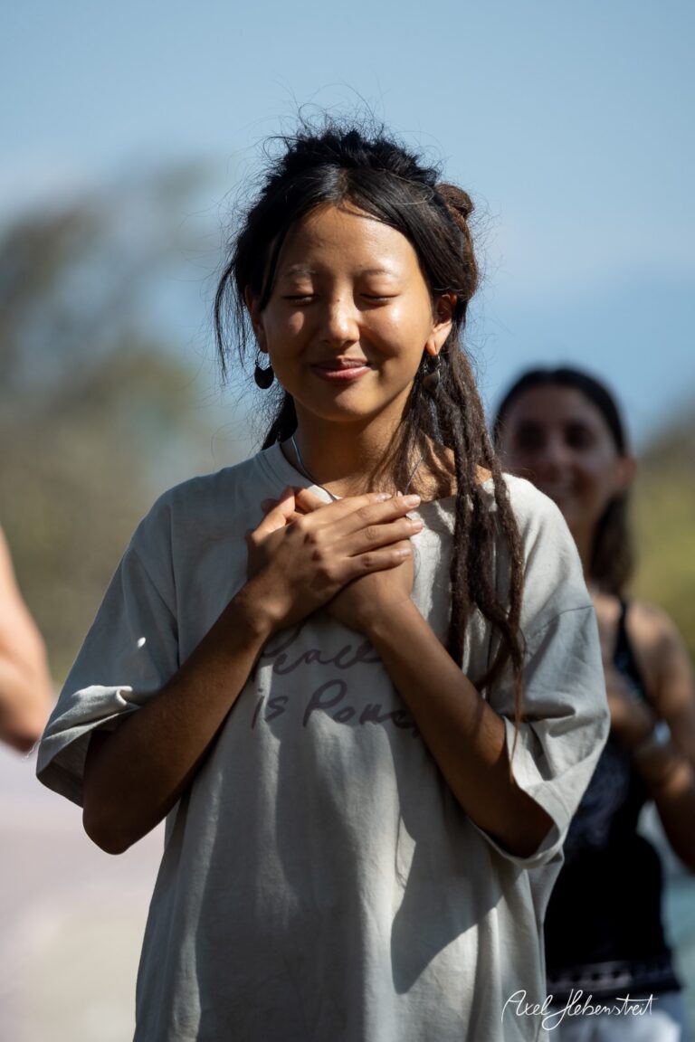 Junge Frau mit Dreadlocks, die die Augen schließt und eine meditative Haltung in freier Natur einnimmt – © Axel Hebenstreit