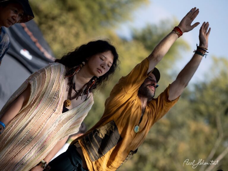 Zwei Personen in einer entspannten Pose während eines Festivals im Freien, umgeben von Natur – © Axel Hebenstreit