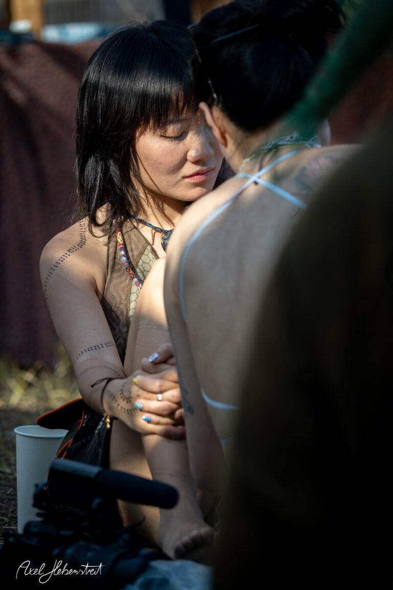Zwei Frauen in einem entspannten Moment bei einem Festival, eine hält die Hände der anderen. – © Axel Hebenstreit