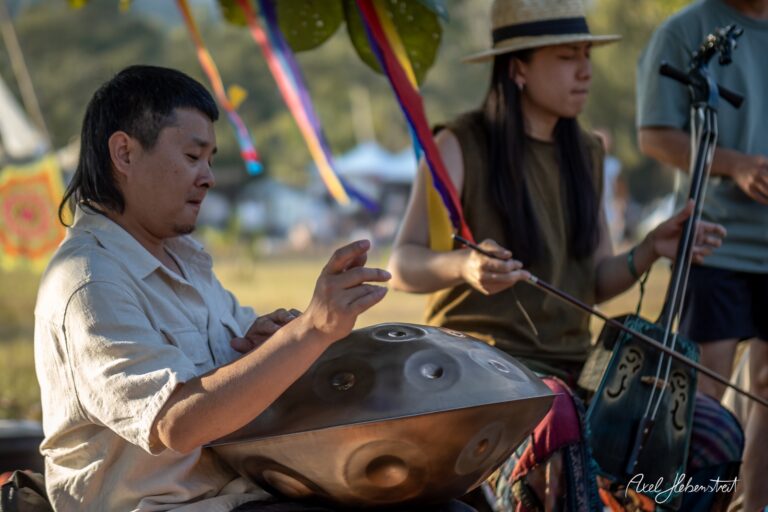 Zwei Musiker spielen harmonisch auf einem Festival; der Mann mit einem Handpan und die Frau mit einer traditionellen Geige. – © Axel Hebenstreit