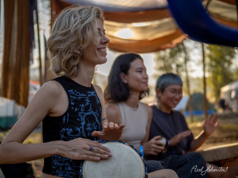 Drei Frauen spielen entspannt auf Trommeln in einer festlichen Umgebung während eines Festivals – © Axel Hebenstreit
