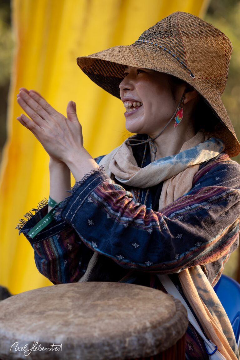 Eine Frau in einem Hut klatscht begeistert zu den Rhythmen des Musikfestivals. – © Axel Hebenstreit