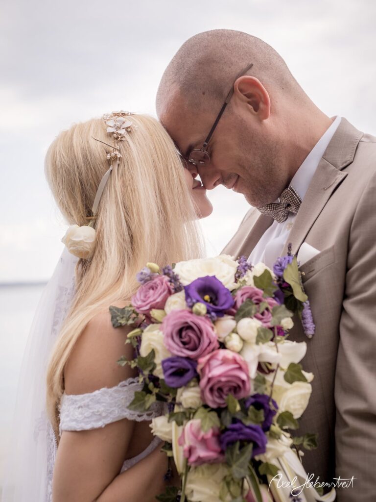 Paar in inniger Umarmung am See mit schöner Blumenstrauß, romantische Stimmung bei einer Hochzeit – © Axel Hebenstreit