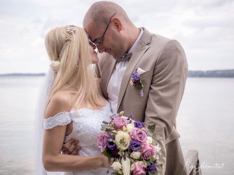 Braut und Bräutigam umarmen sich zärtlich bei der Hafenhochzeit, umgeben von romantischer Stimmung – © Axel Hebenstreit