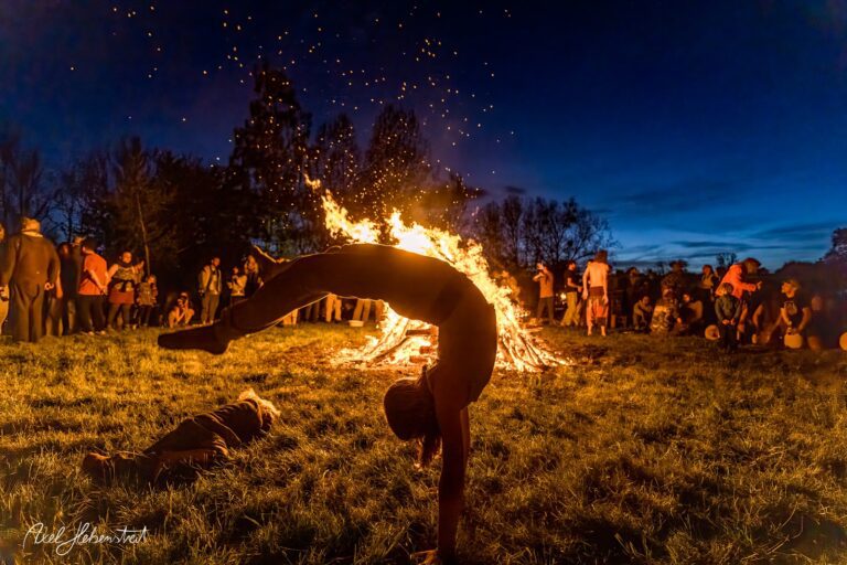 Yoga-Pose vor einem großen Lagerfeuer bei einer festlichen Versammlung in der Natur – © Axel Hebenstreit