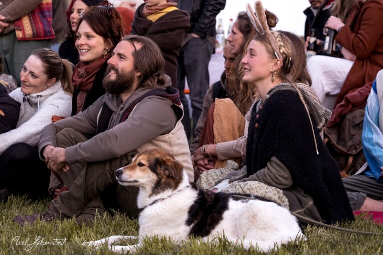 Menschen sitzen entspannt auf einer Wiese, umgeben von Natur und in fröhlicher Festivalatmosphäre. – © Axel Hebenstreit