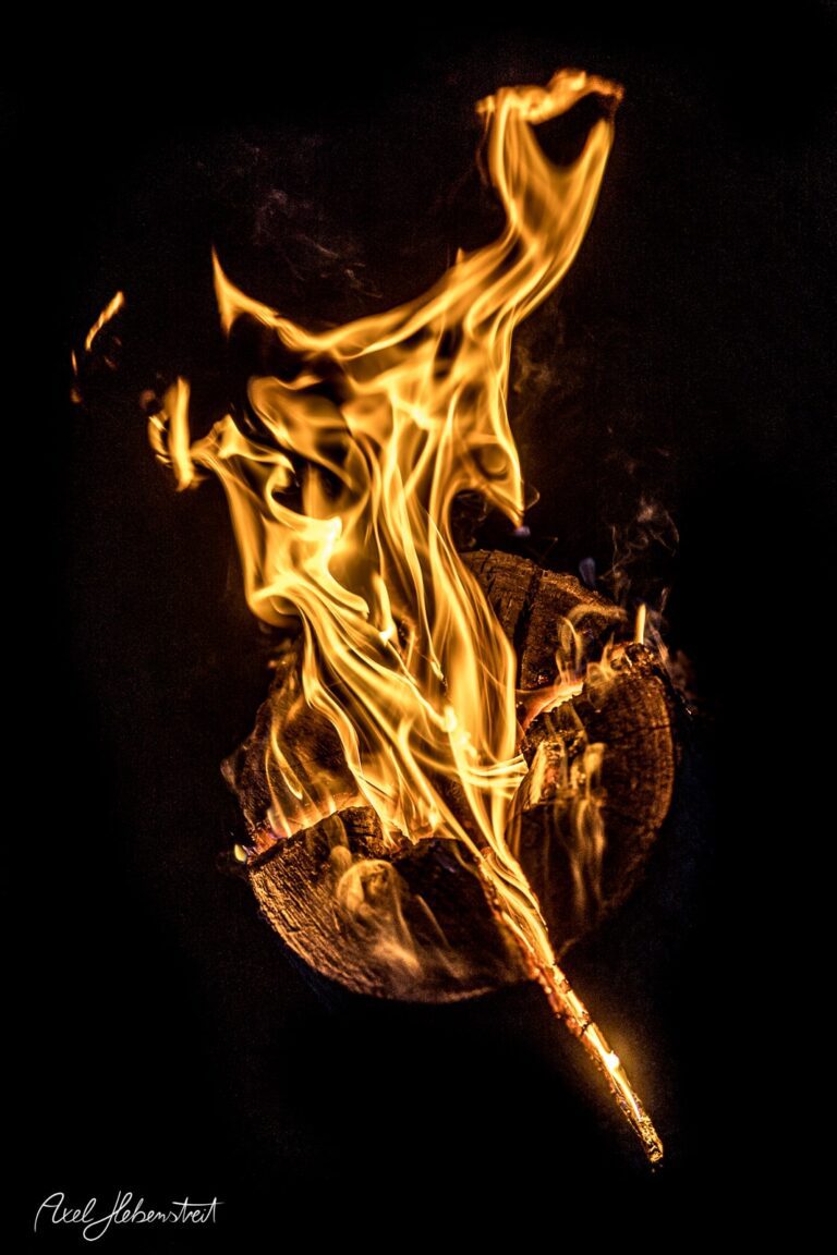 Flammender Stock feuert lebhafte, tanzende Flammen auf dunklem Hintergrund, erzeugt eine mystische Stimmung. – © Axel Hebenstreit