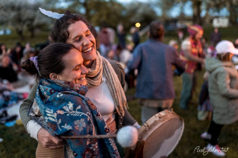 Zwei Frauen umarmen sich fröhlich beim gemeinsamen Musizieren in einer entspannten, festlichen Atmosphäre im Freien – © Axel Hebenstreit