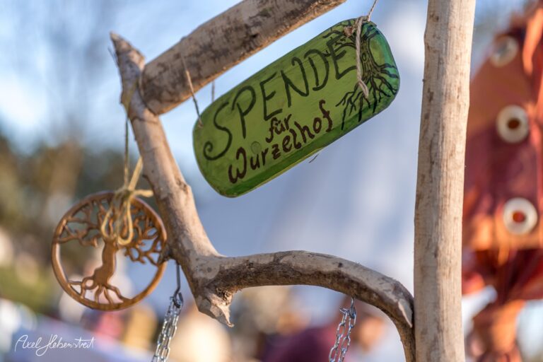 Handgefertigtes Schild mit der Aufschrift "Spende für Wurzelhof" aus Naturmaterialien auf einem Festival. – © Axel Hebenstreit
