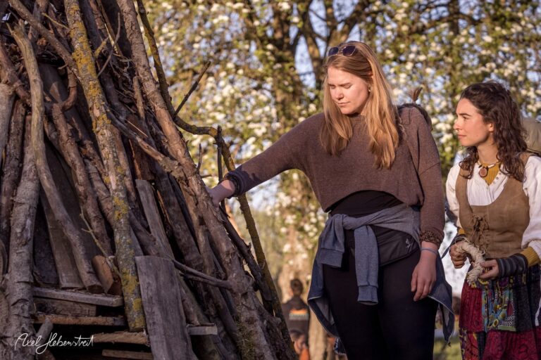 Junge Frauen erkunden eine Holzstruktur inmitten blühender Bäume während eines Festivals – © Axel Hebenstreit