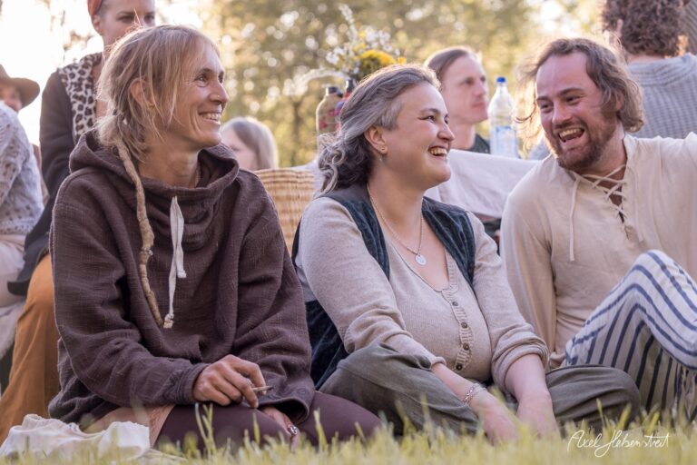 Drei Frauen sitzen fröhlich auf einer Wiese, umgeben von einer entspannten Festivalatmosphäre – © Axel Hebenstreit.