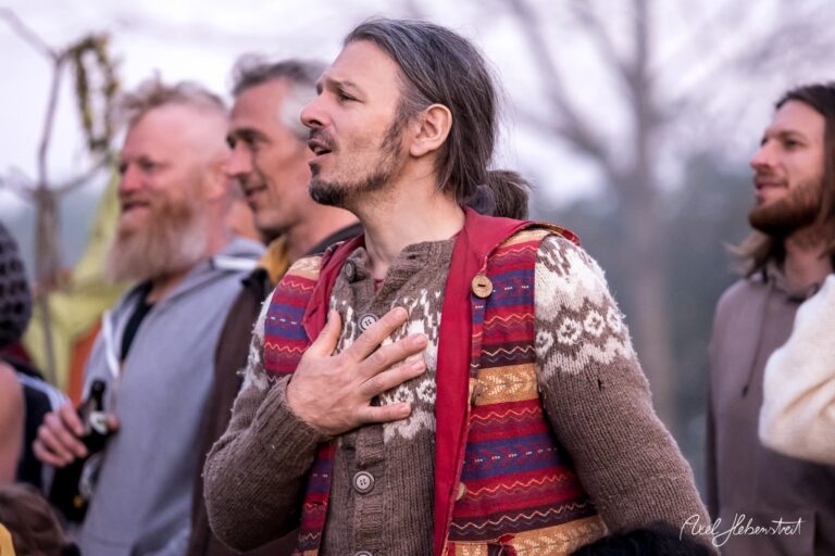 Mann in buntem Kleidungsstil singt und gestikuliert begeistert beim Festival im Freien – © Axel Hebenstreit