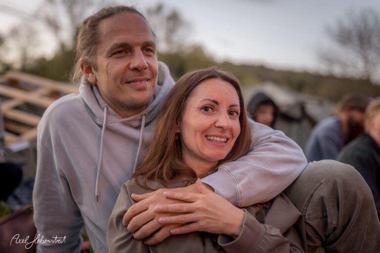 Ein lächelndes Paar umarmt sich liebevoll im Freien während eines entspannten Moments. – © Axel Hebenstreit