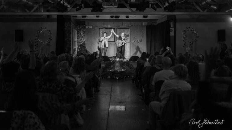 Zwei Musiker treten auf einer Bühne auf, während das Publikum begeistert mit den Händen reagiert – © Axel Hebenstreit