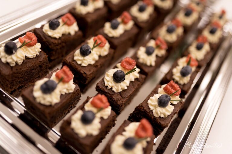 Elegante Schokoladenstückchen mit Sahnehaube und frischen Beeren auf einem silbernen Tablett – © Axel Hebenstreit