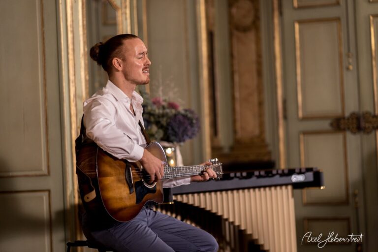 Musiker spielt mit Leidenschaft Gitarre in eleganter Umgebung während eines intimen Auftritts – © Axel Hebenstreit