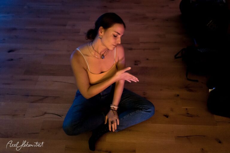Eine junge Frau sitzt meditativ auf dem Boden, umgeben von sanftem Licht. – © Axel Hebenstreit