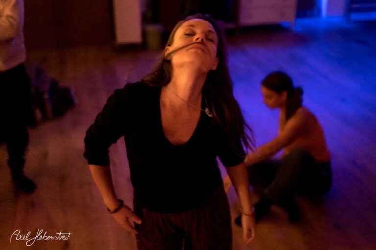 Eine tanzende Frau mit geschlossenen Augen und erhobenem Kopf, umgeben von sanftem Licht in einem kreativen Raum – © Axel Hebenstreit